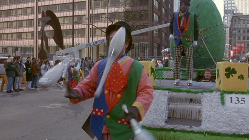 A juggler with pins in front of a parade float with a Picasso bronze stature in the background