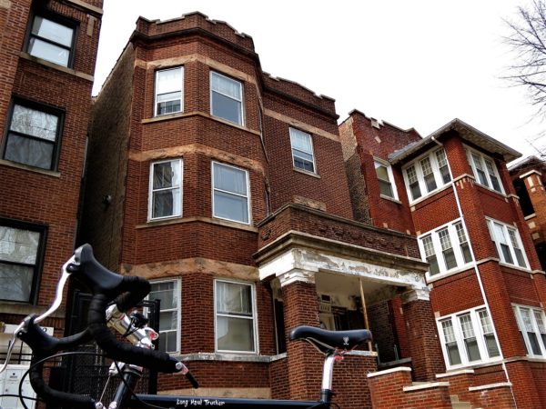 A tour bike in front of a typical Chicago red brick three flat