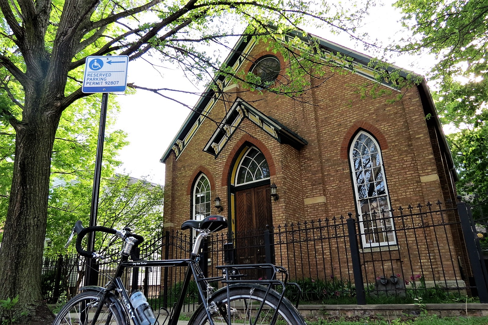 A standing tour bike with a one story late 1800s one story brown brick church behind.