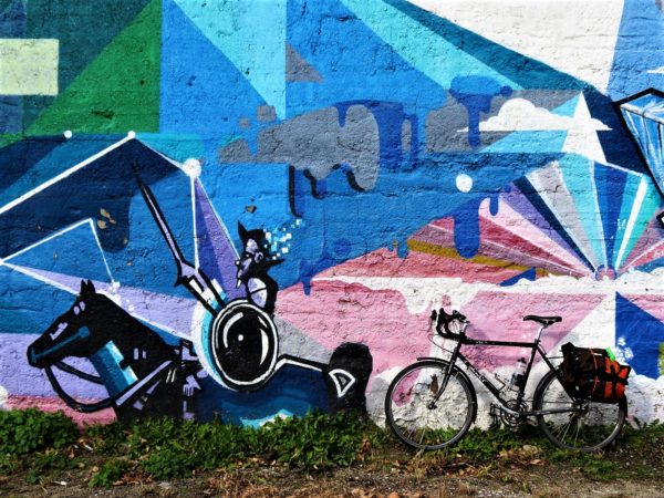 A tour bike leaning on a colorful mural of Don Quixote.