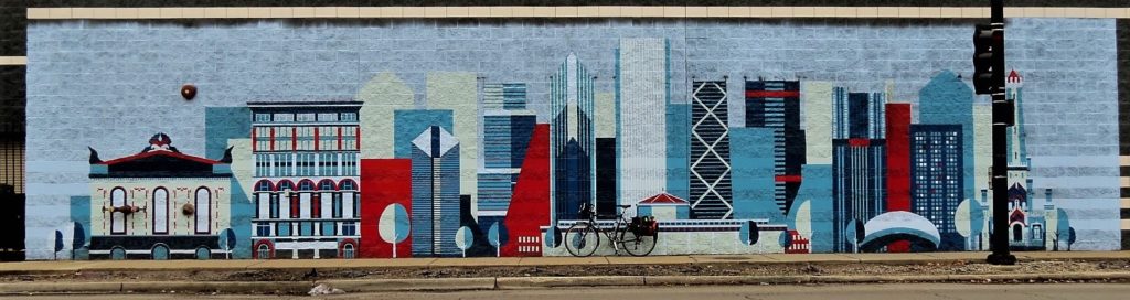 A tour bike leaning on a mural of cartoon style Chicago skyline.