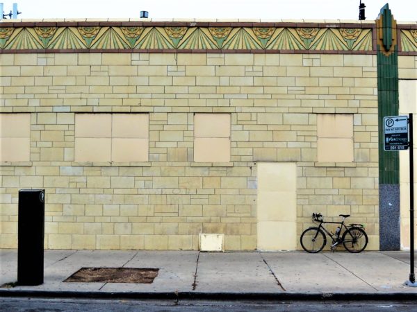 A tour bike leaning on a pale green tiled wall with art deco green and yellow floral details.