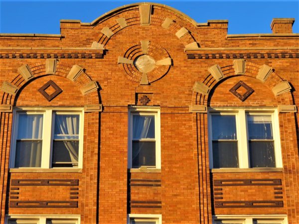 A tan brick facade with brown and yellow brick patterns.