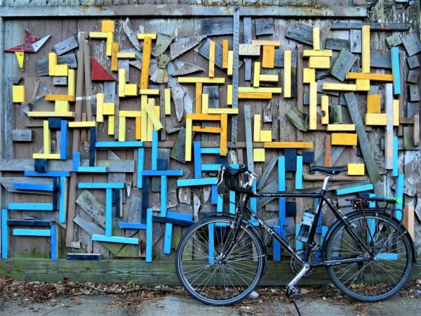 A tour bike leaning on a yellow and blue painted wood block wall arrangement.