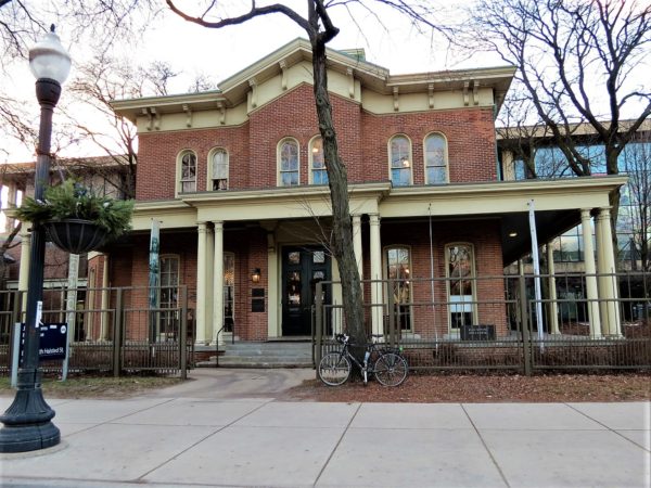 A tour bike in front the red brick wrap around porch 1880s Hull House at UIC.