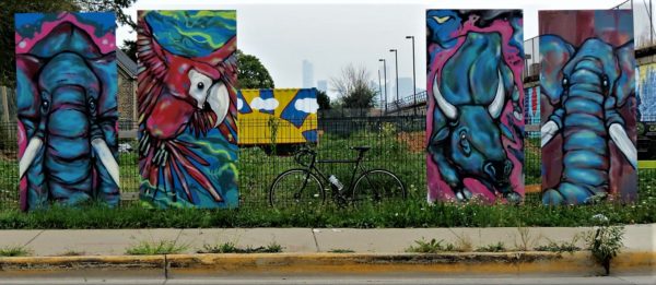 A tour bike leaning between four rectangular panels painted with animals by Bunny XLV at Chicago FarmWorks.