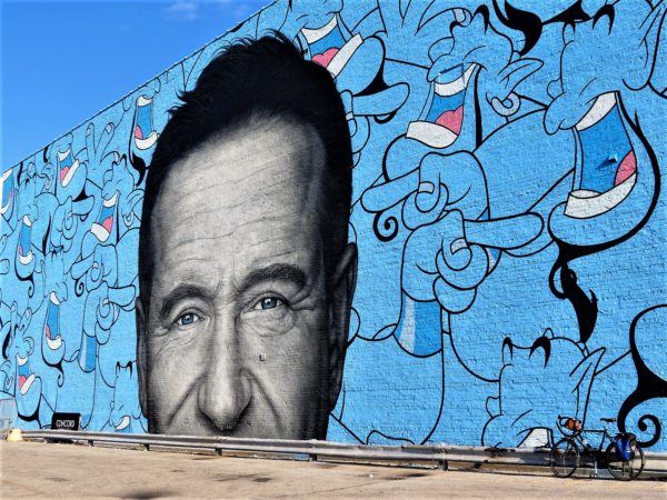 A tour bike leaning on the Jerkface and Owen Dippie Genie/Robin Williams mural.