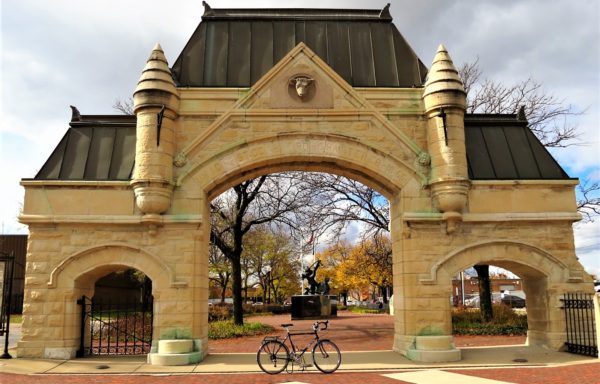 A tour bike standing in front of three entry yellow limestone 1870s Burnham & Root Union Stockyards Gate.