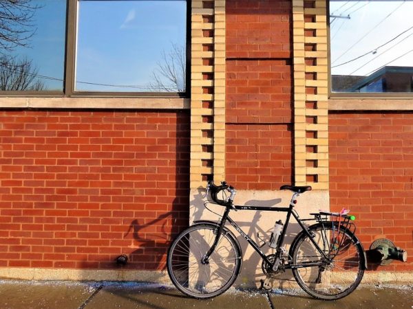 Touring bike leaning in a red brick wall with yellow brick accents.