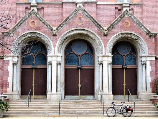 Bicycle on the front steps of a church arched entry way.