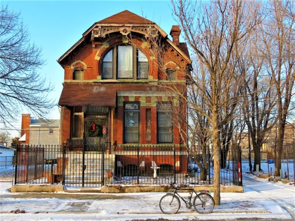 Bicycle in front of a snowy 19th Century house with a large curved 2nd story window.