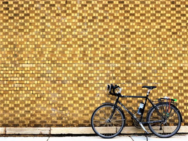 Bicycle leaning on black and tan patterned brick wall.