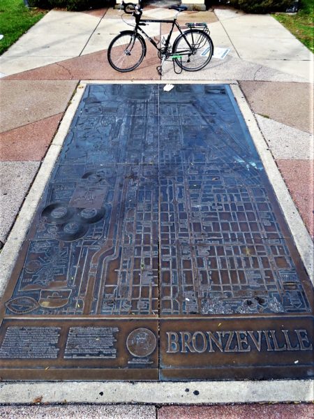 A bronze map of the Bronzeville neighborhood on the ground and a tour bike.