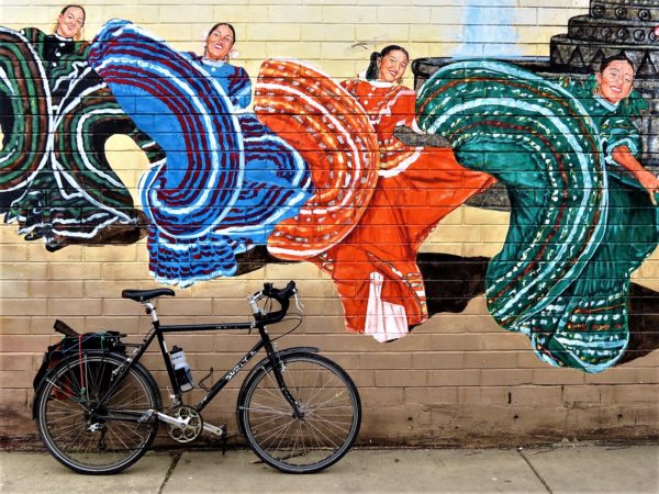 A bicycle in front of a dancing Mexican women mural during a tour ride.