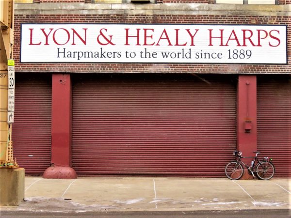 A tour bike leaning on the red roll garage door of Lyon & Healy Harps.