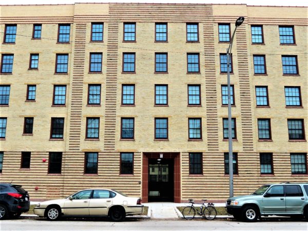 Red brick pattern on yellow building facade with a bike parallel parked in front.