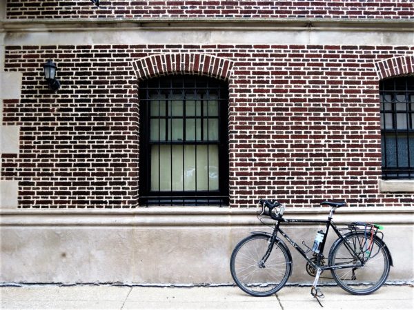 Bicycle leaning on a dark red brick wall.