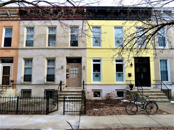 A tour bike standing in front of an differently painted Italianate row house