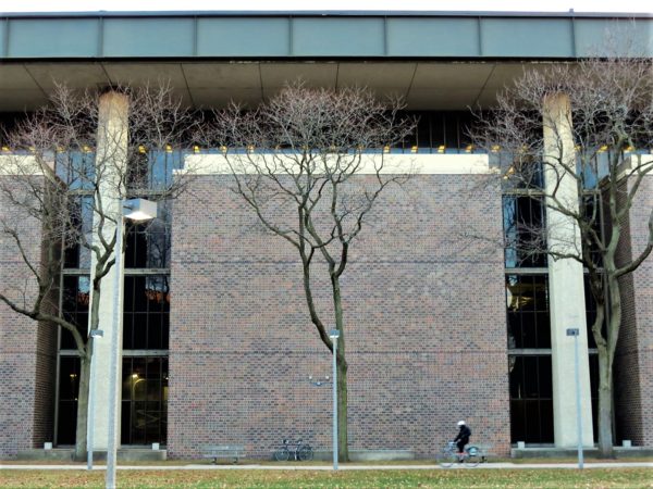 A tour bicycle and cyclist in front of a Brutalist building.