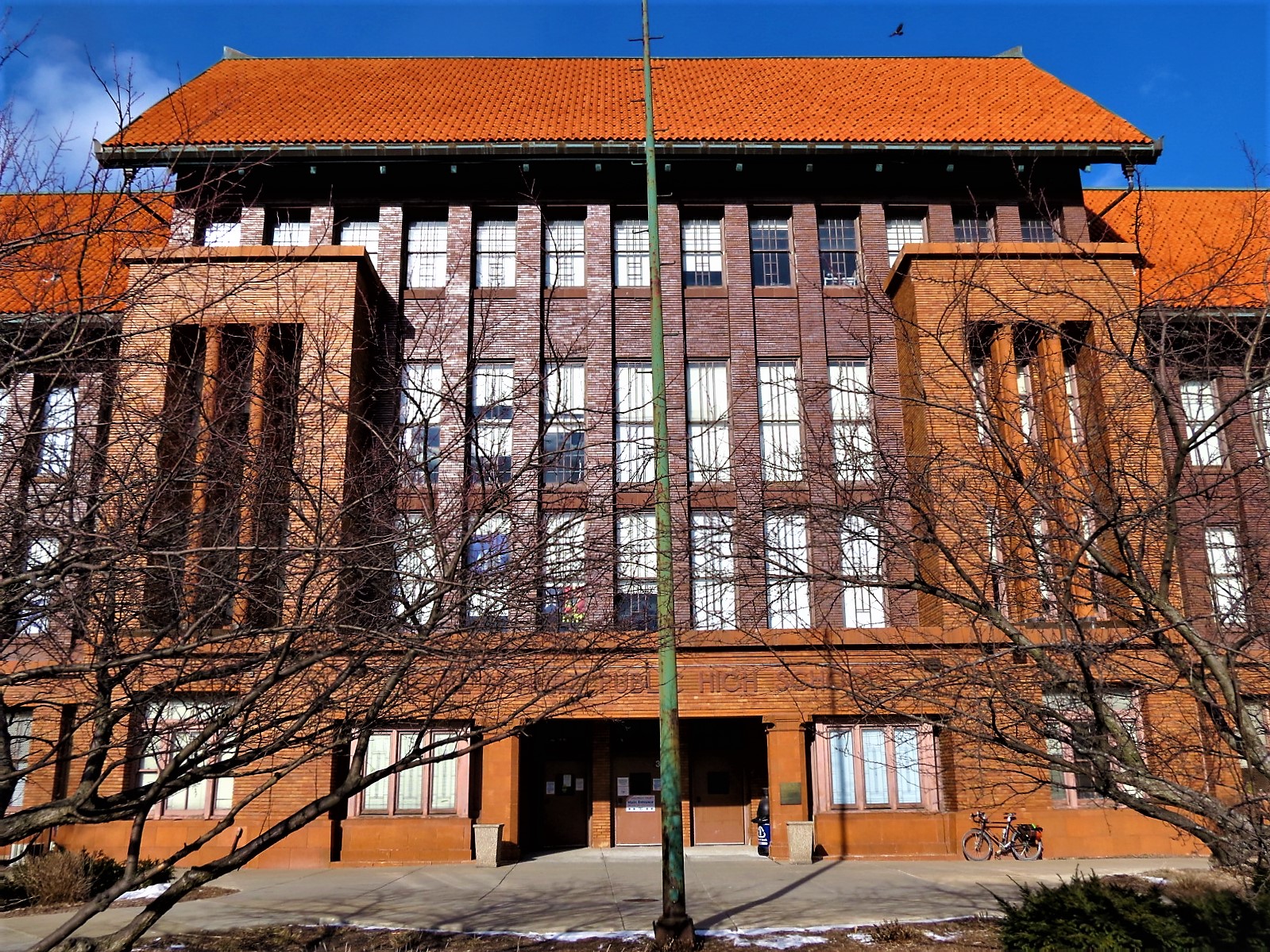 A tour bike leaning on Prairie School style building with gold and brown brick