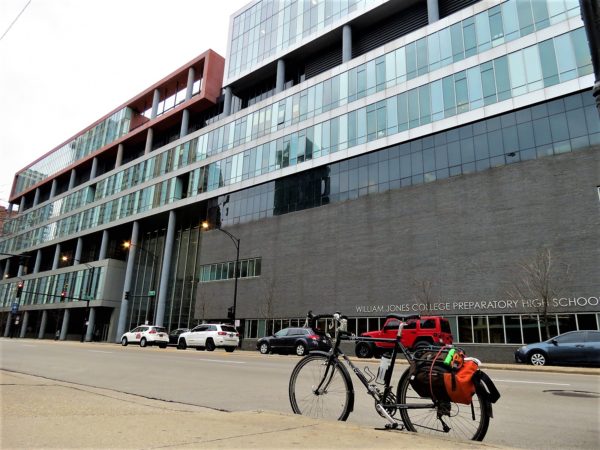 A tour bike standing in front of eight story modern building