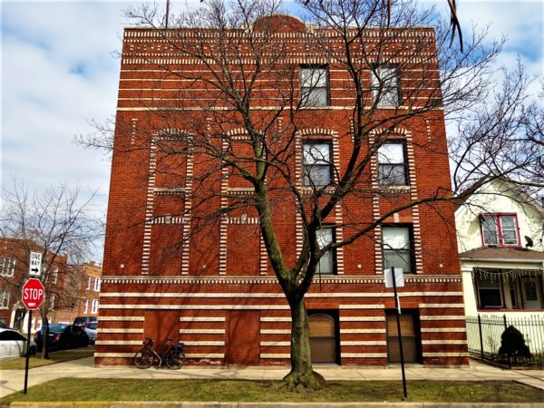 White brick patterns on red brick building with a bicycle during a tour ride.