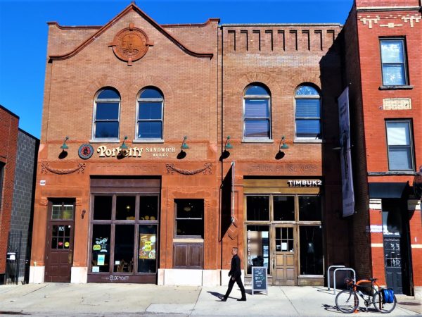 Red brick former fire house buildings with shops on the first floor and a tour bike in front