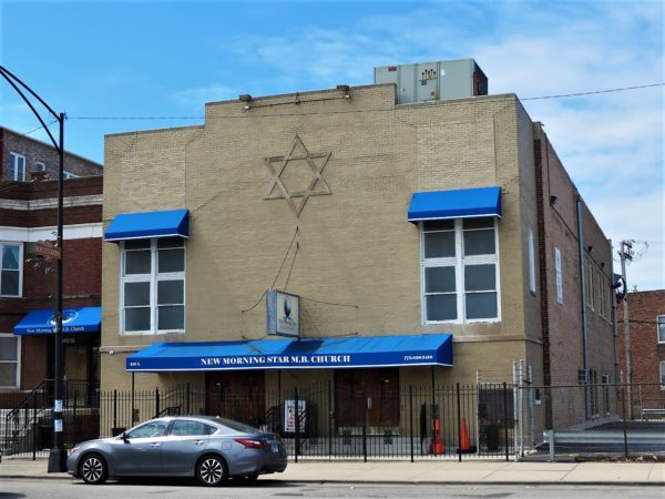 A boxy former synagogue now church with a visible Star of David and blue awnings.