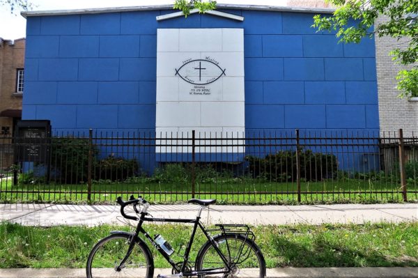 A blue and white former synagogue now church with a tour bike in front.