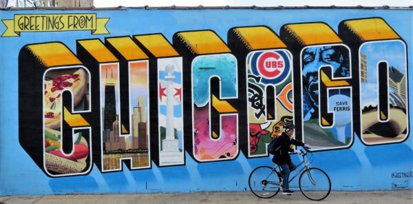 CBA tour rider riding past the Greetings from Chicago mural.
