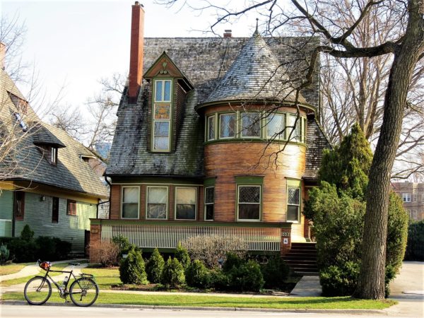 Multi toned brown wood home with rounded bay window and tour bike in front.