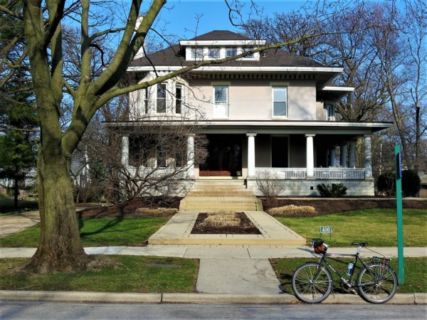 Tour bike in front of prairie style two story home.