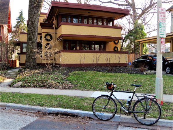 Yellow and red Prairie style home with tour bike in front.