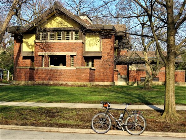 Tour bike in front of red brick gabled roof Prairie style home.