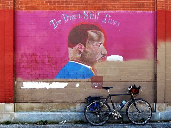 Damaged martin Luther King mural with a leaning tour bicycle.