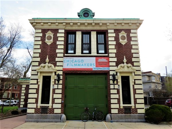 Two story red brick building with yellow accents and a tour bike leaning on the green garage door