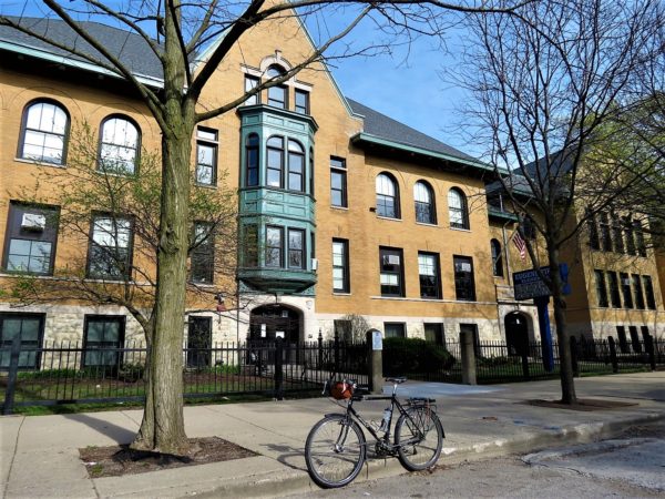 Yellow brick school with a green bay window and a tour bike in front.