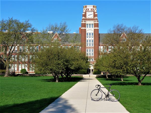 Red brick Academic Gothic style school building with a tour bike standing in front.