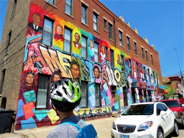 A CBA bike tour rider looking at the Latinos Progressando sponsored Delilah Salgado / Pablo Serrano Americanos mural in Pilsen depicting social justice icons.