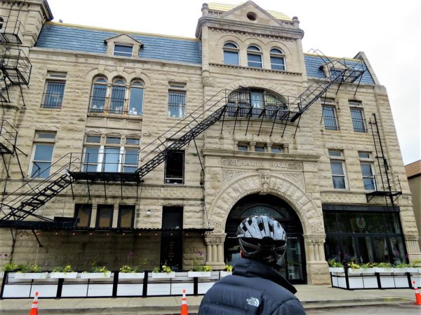 A CBA bike tour rider looking at the 1890s greystone Thalia Hall with a long black fire escape.