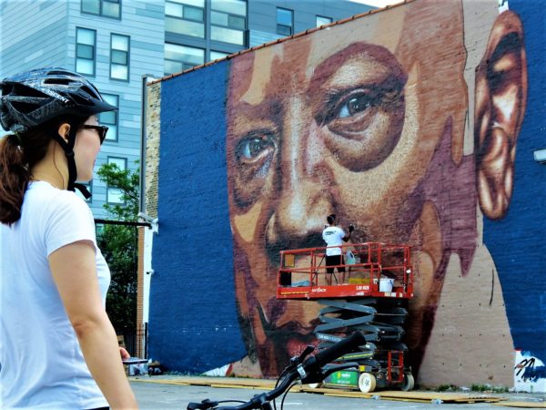 A CBA tour rider watching CobreArt putting up a ;arge mural of Quincy Jones.