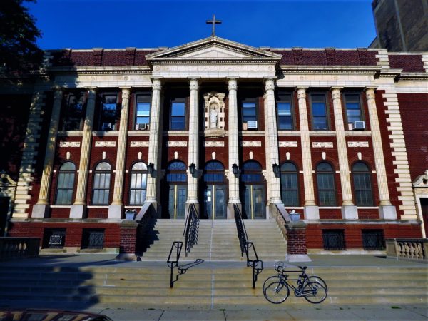 A tour bike leaning on the front steps of a Neo-Classical red brick and white marble church