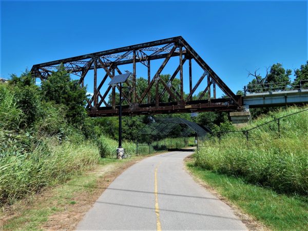 A tour bike leaning under a rail road bridge over the bike path