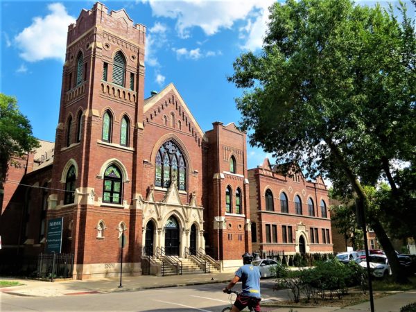 A CBA bike tour rider looking at a 1905 red brick a cream terra cotta former church converted into condos.
