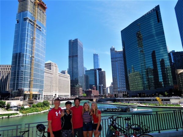 Five CBA bike tour riders at the confluence of the Chicago River with skyscrapers in the background.
