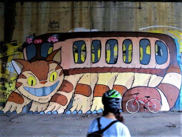 A CBA bike tour rider looking at a mural of a large cat with bus seating.