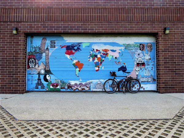 A tour bicycle leaning a roll door painted with a world map