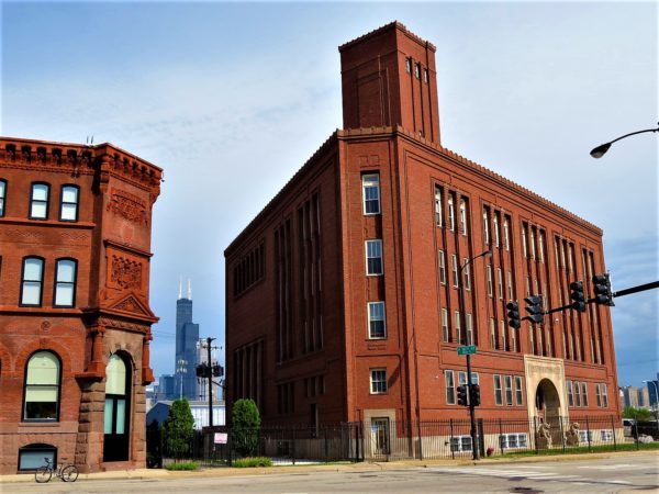 A tour bike standing in front of two red brick buildings, one from the 1880s, the other Priaire Style from the 1900s, with the Willis Tower seen between the two
