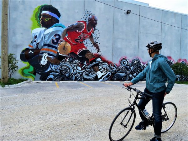 A CBA bike tour rider looking at a large mural of Walter Payton and MIchael Jordan