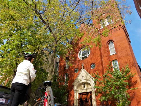 A CBA bike tour rider looking up at a red brick former church.